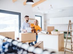 Homeowners unpacking boxes in a newly renovated modern kitchen during a home improvement project.