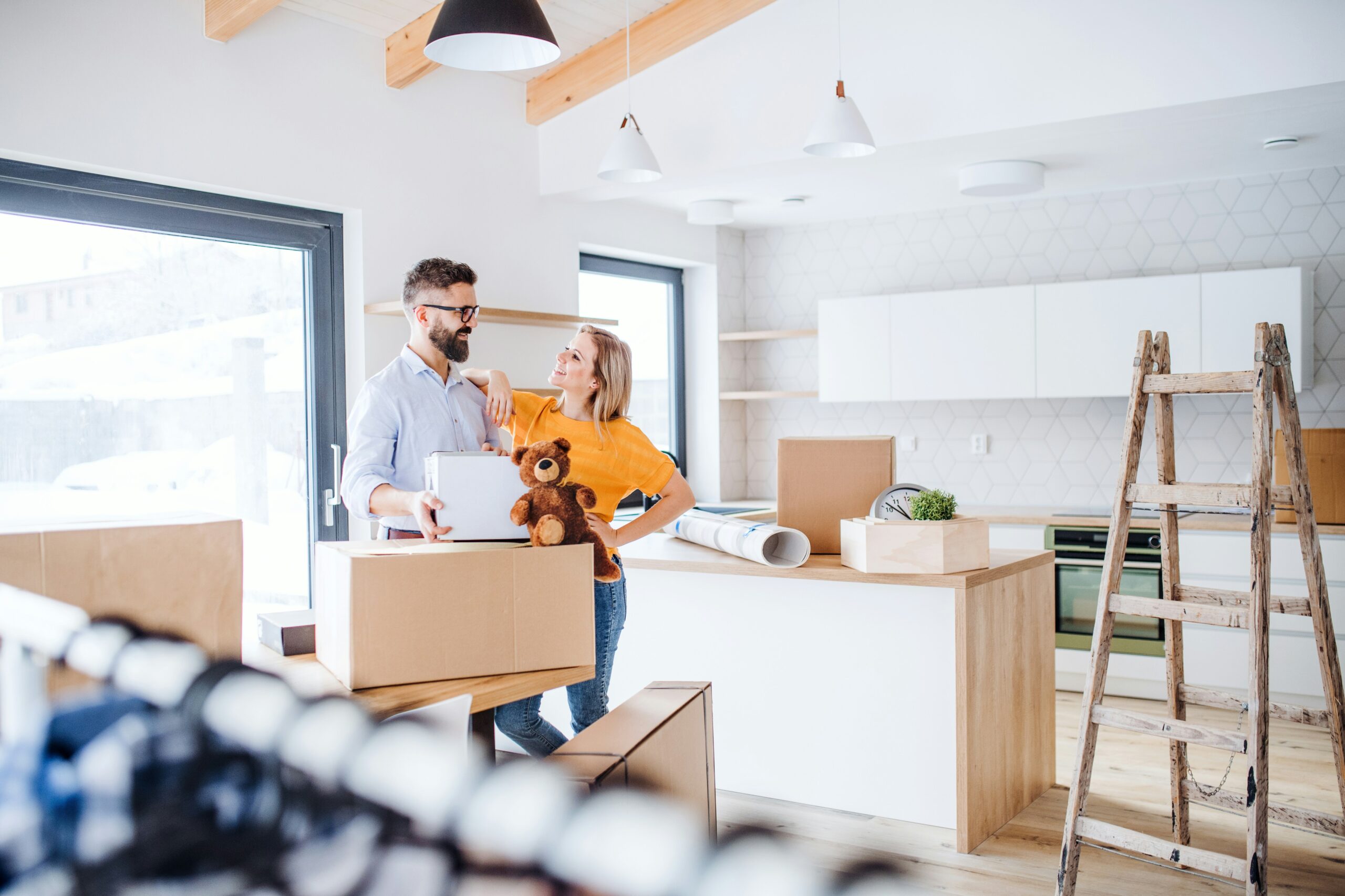 Homeowners unpacking boxes in a newly renovated modern kitchen during a home improvement project.